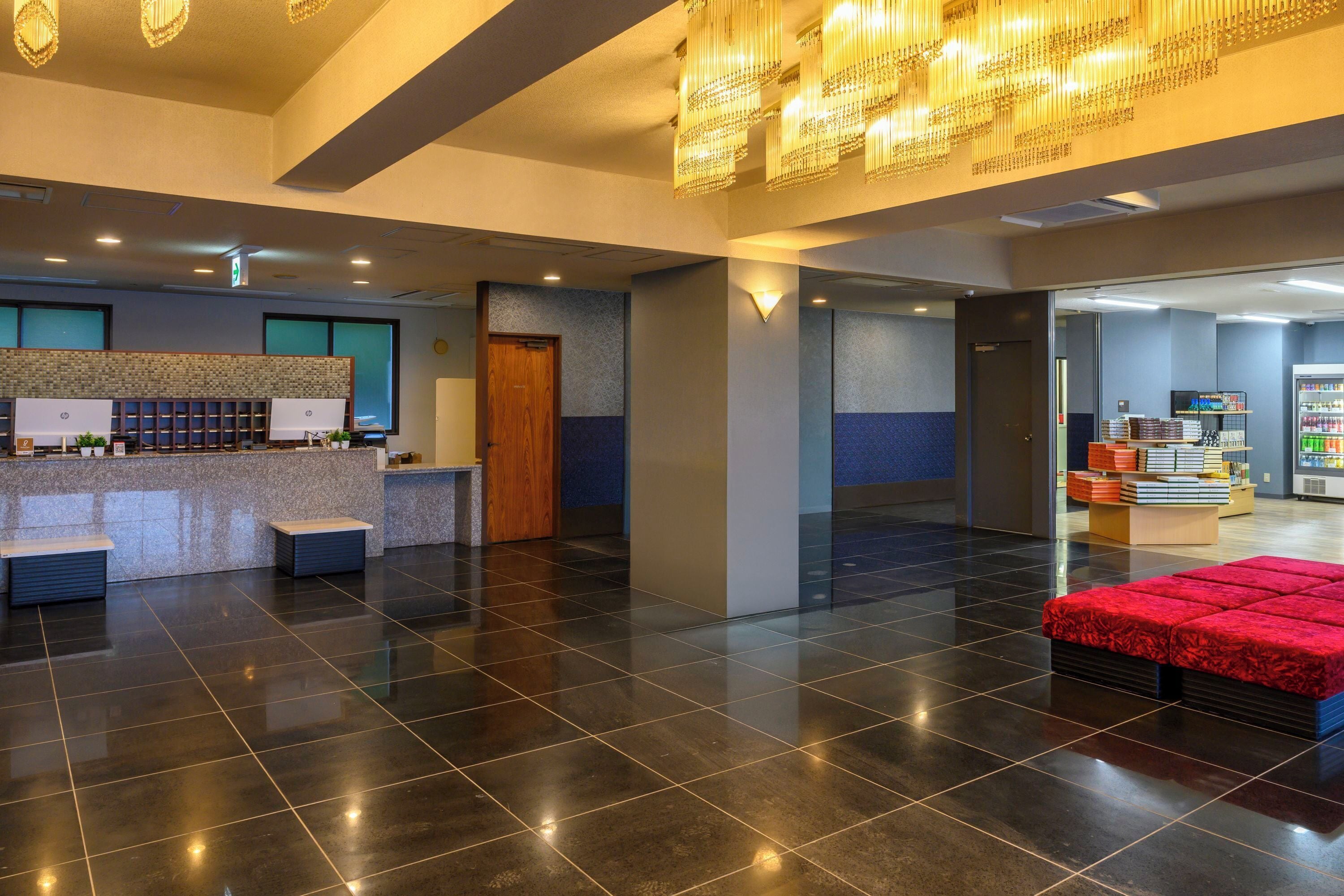 A modern hotel lobby with a reception desk, seating area, and a vending machine.