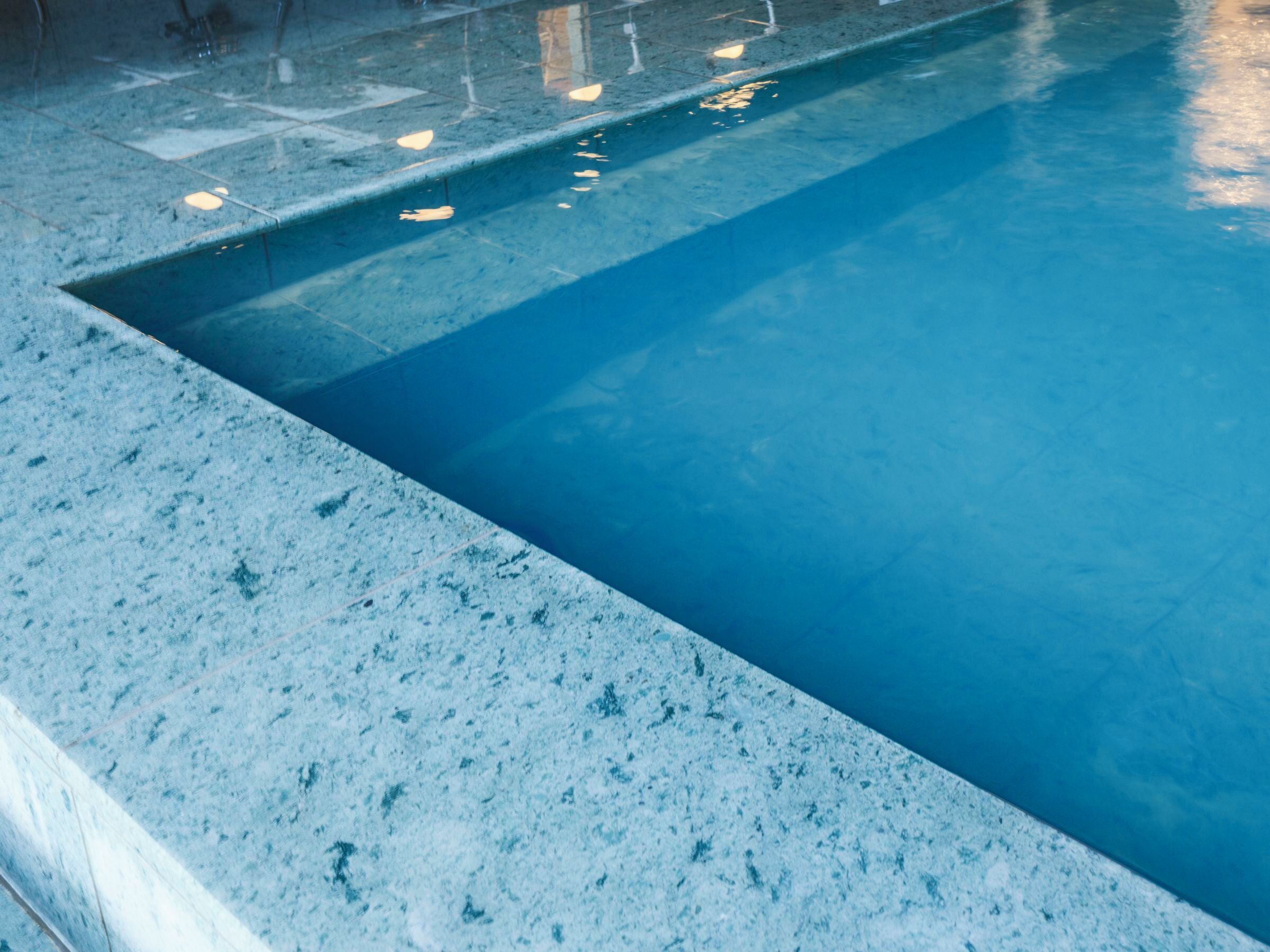 A pool with a textured edge and clear blue water.