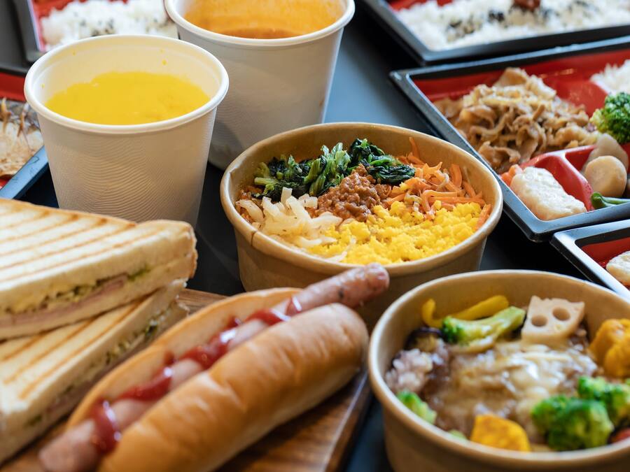 Diversas opciones de comida, incluyendo sándwiches, un perro caliente, y tazones de verduras y arroz.