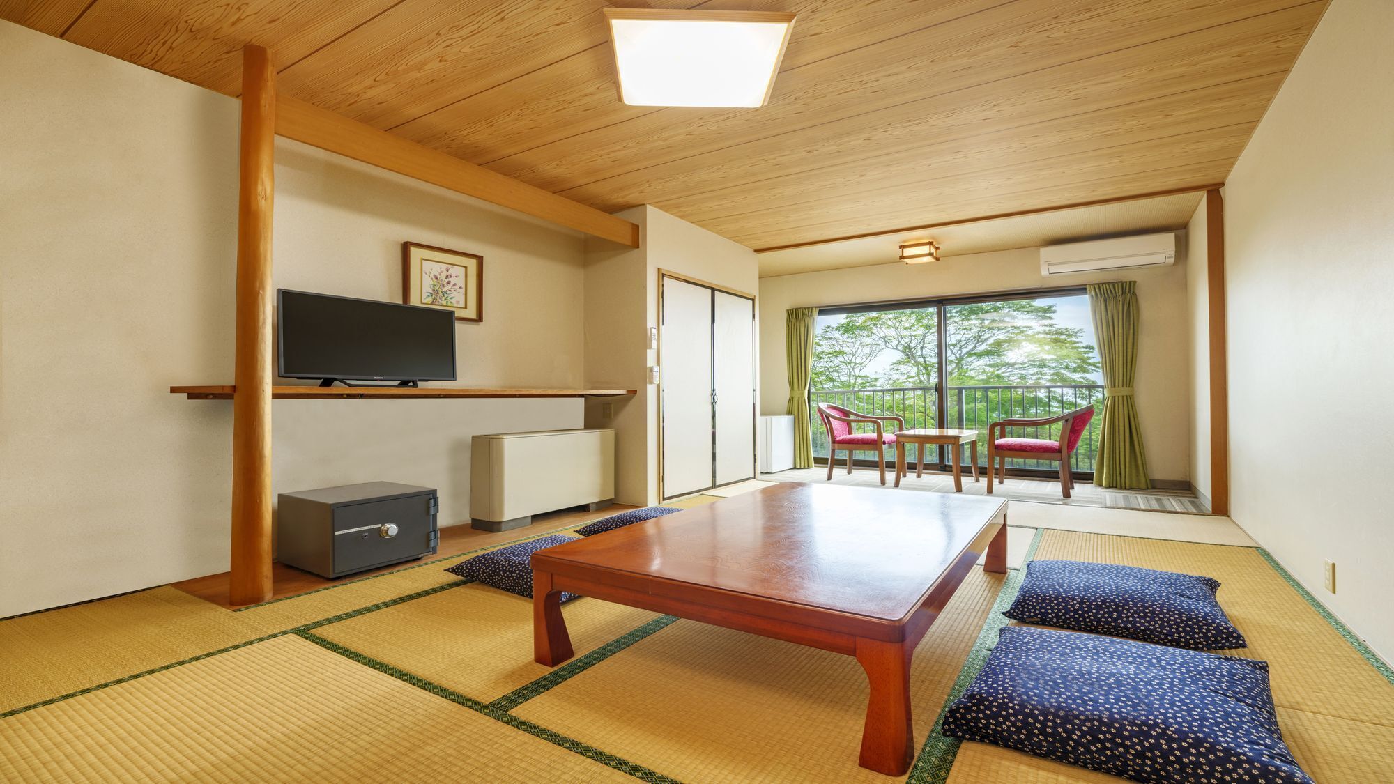 A traditional Japanese-style room with tatami flooring, a low table, a television, and a sliding door leading to a balcony with a view.