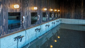 Baño público con varios lavamanos, espejos y apliques de pared iluminados.