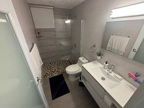Ein modernes Badezimmer mit Toilette, Waschbecken und Dusche.