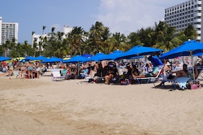 Una spiaggia affollata con numerosi ombrelloni blu che offrono ombra.