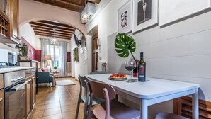 A modern kitchen with a dining area, a large green plant, and a wine bottle on the table. - Wine Apartments Florence Sangiovese (Firenze)