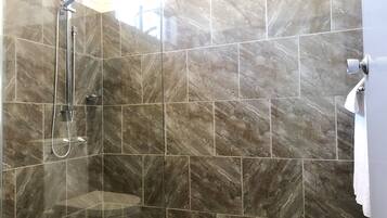 A modern bathroom with a shower area, marble tiles, and a toilet.