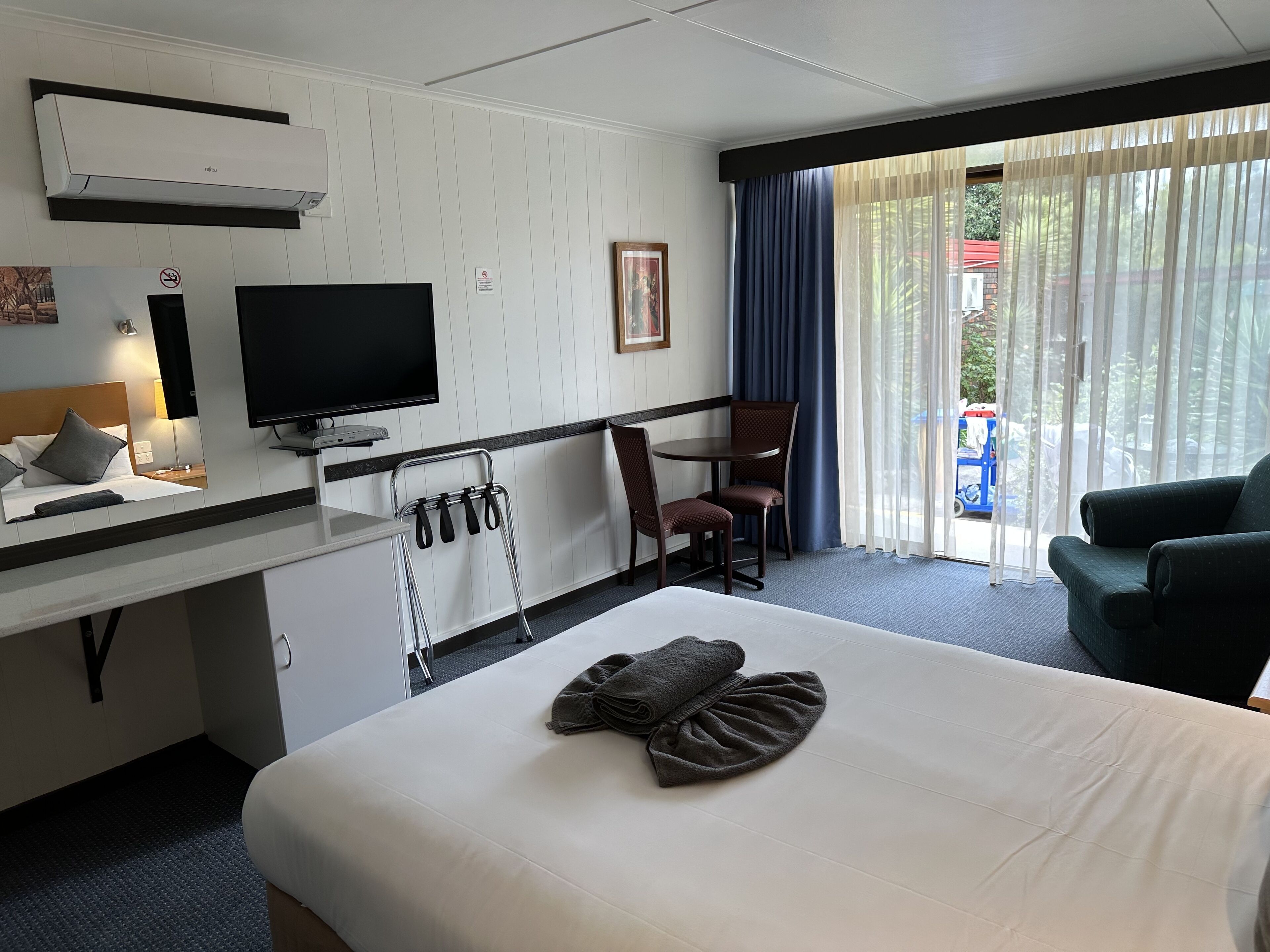 Une chambre d’hôtel comprenant un lit, un bureau avec un téléviseur à écran plat, une chaise, un canapé et une fenêtre avec des rideaux.