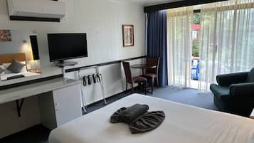 Une chambre d’hôtel comprenant un lit, un bureau avec un téléviseur à écran plat, une chaise, un canapé et une fenêtre avec des rideaux.