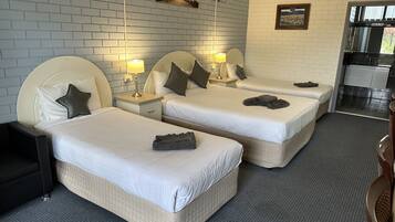 Une chambre d’hôtel avec deux lits, chacun doté d’une tête de lit, de tables de chevet avec des lampes et d’une petite table de nuit.