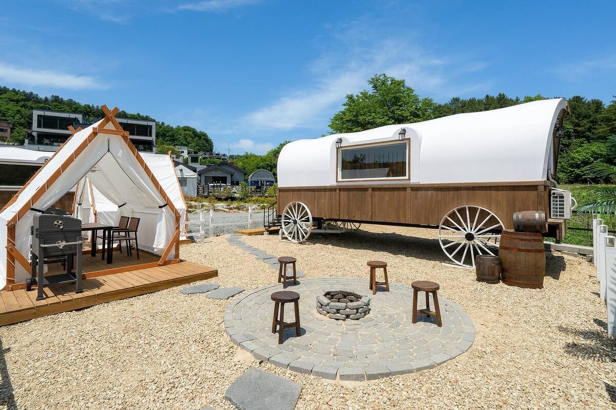 Un terrain de camping rustique avec une tente, une table à manger en bois et un foyer.