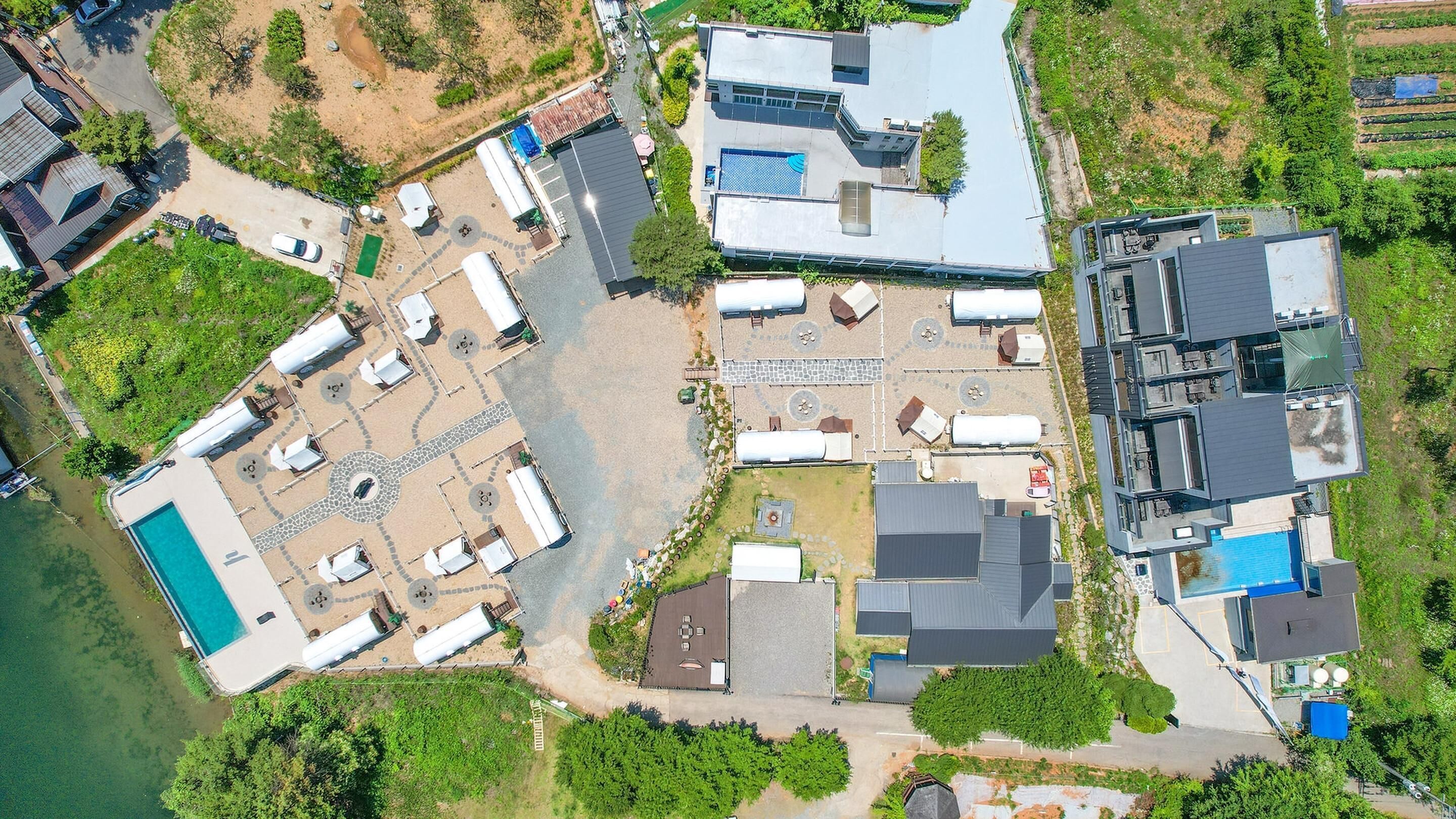An aerial view of a residential area with a swimming pool, multiple buildings, and a large open space with a gazebo.