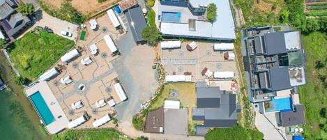 An aerial view of a residential area with a swimming pool, multiple buildings, and a large open space with a gazebo.