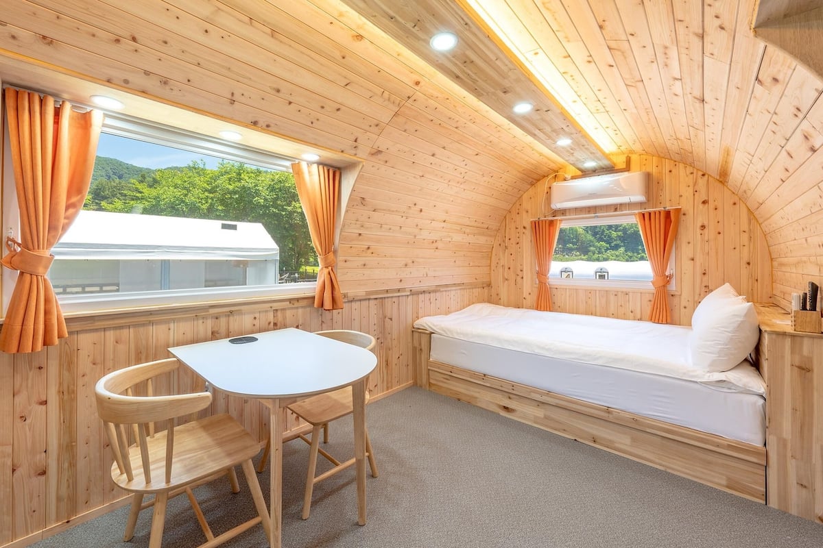 Une chambre confortable dans un chalet, avec un lit, une petite table et deux chaises.