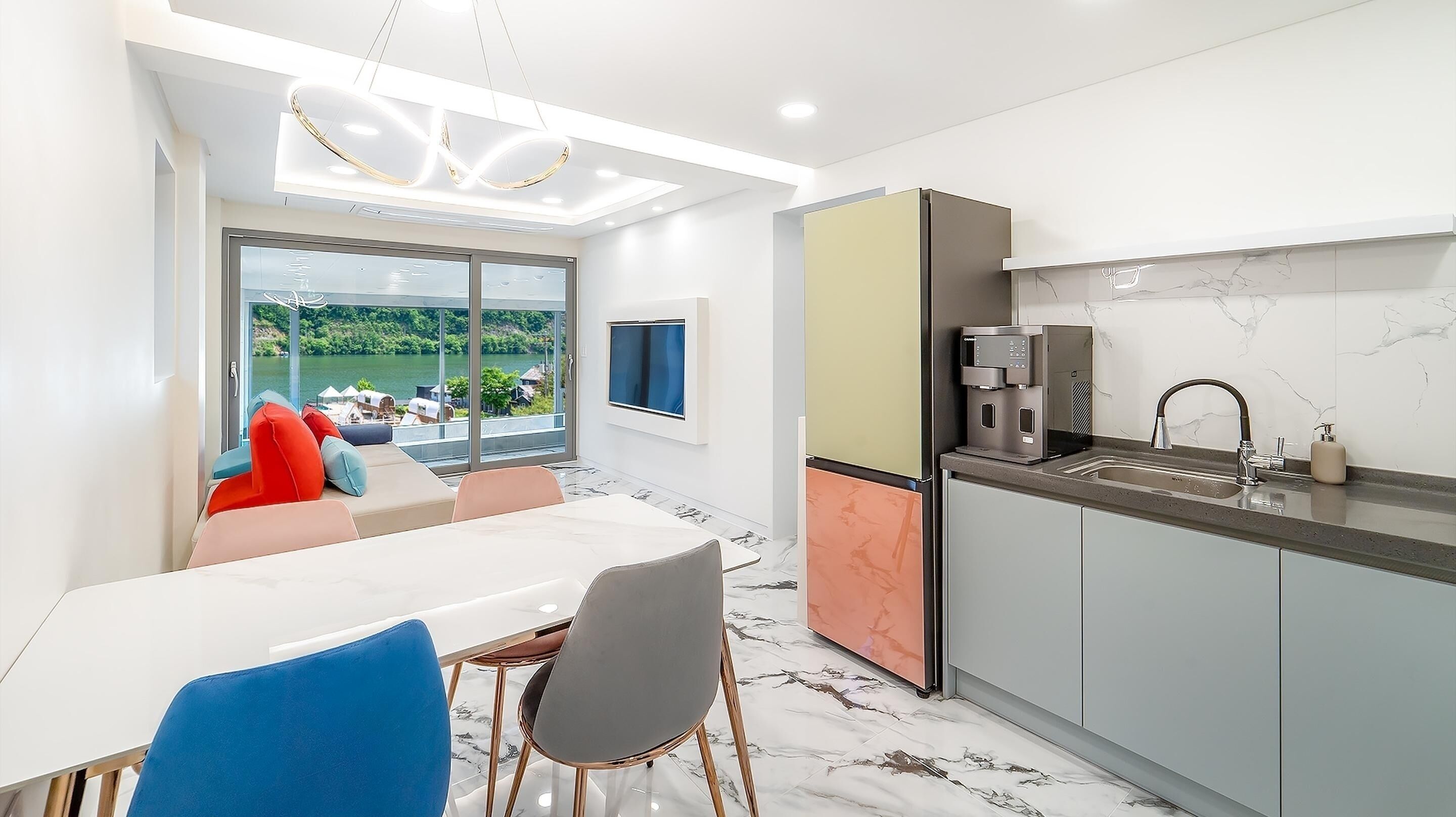 Una cocina moderna con cafetera integrada, un lavamanos y un comedor con mesa y sillas.