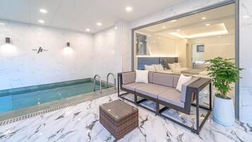 Relax by the pool in a spacious room with a glass pool, wicker sofa, and comfortable seating area.