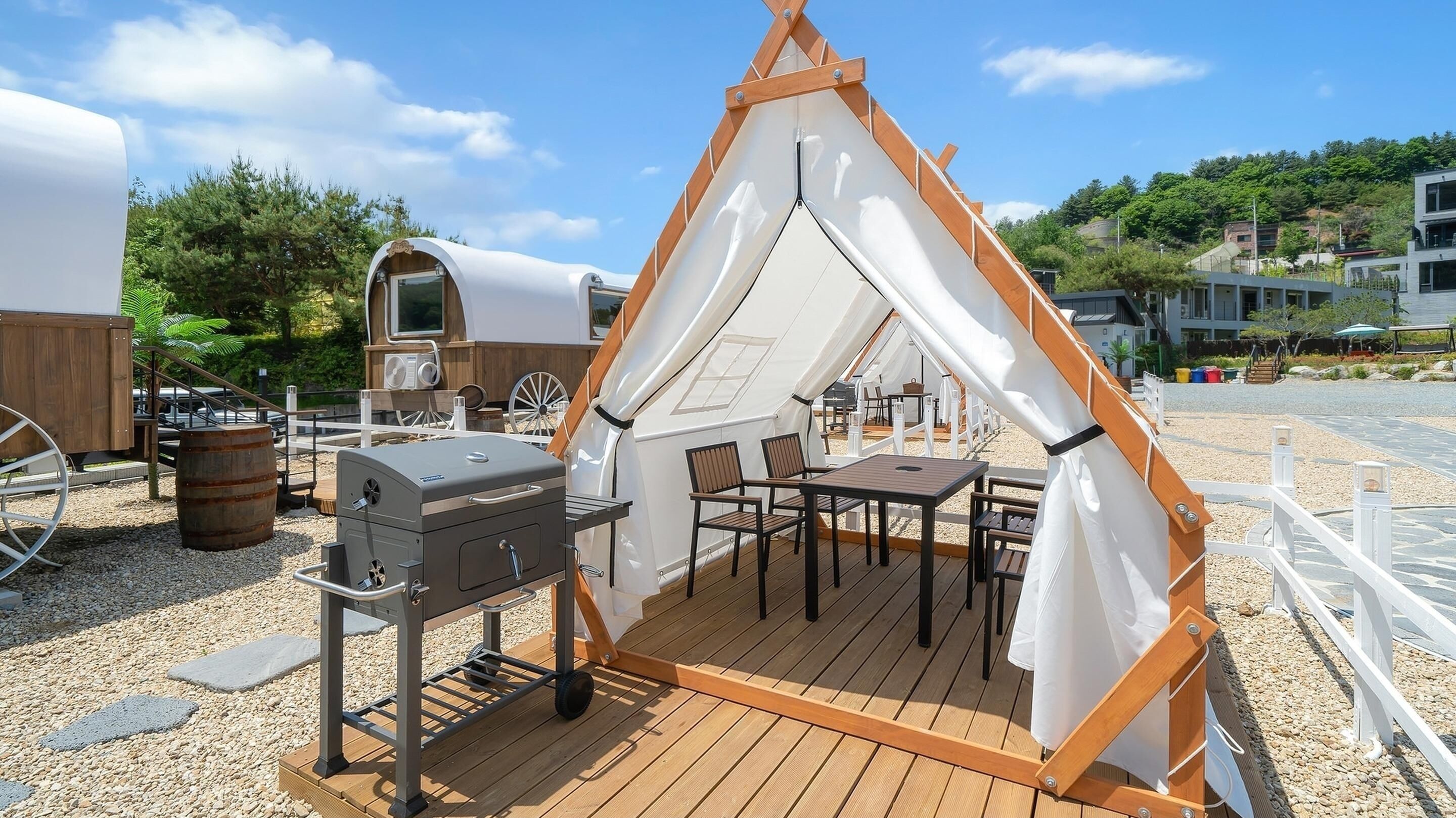 A tented outdoor area with a barbecue grill and seating.