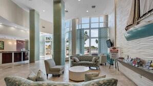 A spacious lobby with a reception desk, seating area, and large windows offering views of the outdoors.