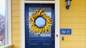 A front door with a wreath, a welcome sign, and a porch with a doormat.