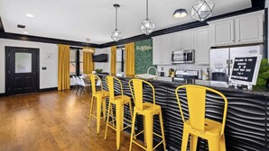 A modern kitchen with white cabinets, a black countertop, and yellow bar stools.