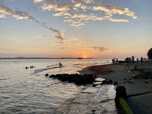 A beach scene with a sunset, calm water, and people on the shore. - Cat house (Cartagena de Indias)