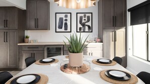 Een moderne eetruimte met een lange tafel voor vier personen, omringd door donkere houten kasten en een groot raam.