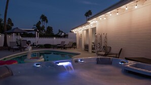 Een deel van het zwembad met een jacuzzi, ligbedden en een pergola.