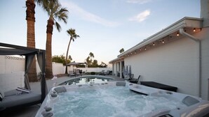 Een bubbelbad met loungestoelen en een overdekt terras.