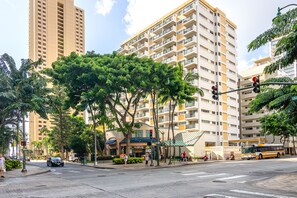 Un immeuble à plusieurs étages doté de balcons, un arrêt de bus et un passage piéton.