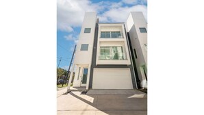Un edificio moderno de dos pisos con techo plano, garaje y cielo despejado.