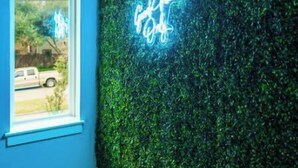 Una habitación con ventanal, un letrero de neón y una pared verde.