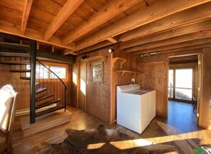Stairs lead to an upper level, with a washing machine and framed poster in this cozy room.