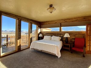 Relax in this serene bedroom with a large bed, bedside tables, and a comfortable chair, offering a stunning view of the surrounding mountains.