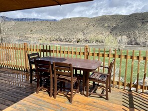 Enjoy a serene riverside view from this deck, surrounded by lush greenery and a hilly landscape.