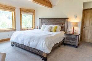 Een slaapkamer met een groot bed, een houten hoofdeinde, nachtkastjes en een lamp.