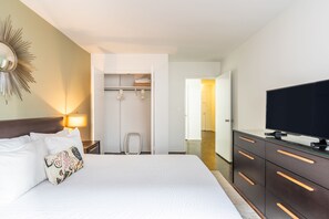 A hotel room with a bed, a television, a wardrobe, and a walk-in closet.