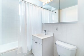 A modern bathroom with a white sink, mirror, and toilet.