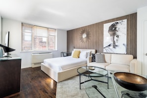 Une chambre moderne avec un grand lit, une table basse en verre, un canapé et un miroir fixé au mur.