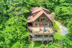 Una cabaña de madera con terraza, rodeada de un bosque denso.