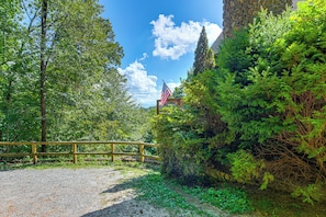 A gravel path leading to a wooden fence, surrounded by lush greenery and a stone wall. - Smoky Mtn Cabin by Cataloochee Valley Elk Viewing! (Waynesville)