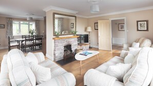 A living room with a fireplace, a dining area with a table and chairs, and a seating area with sofas. - Bay View Cottage 3 bedroom house VRBO (County Kerry)