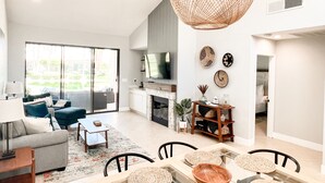 A modern living room with a sofa, coffee table, and dining area. - Palm Valley Getaway with all the amenities & golf water view! (Palm Desert)