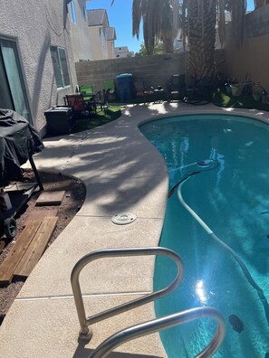 A swimming pool with a metal ladder, surrounded by patio furniture and a palm tree. - Enjoy your stay in a clean, safe environment easy access to freeways (Las Vegas)