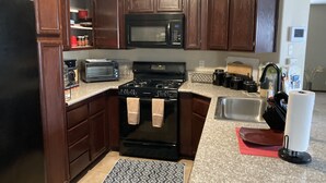 A kitchen with dark wooden cabinets, a black stove, a microwave, a toaster, and a sink. - Enjoy your stay in a clean, safe environment easy access to freeways (Las Vegas)