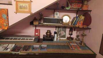 Una stanza con scaffale contenente un forno a microonde, libri, oggetti decorativi e una cornice con un'immagine.