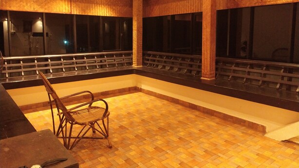Una habitació amb sòl de fusta, una cadira i una finestra amb vista al cel nocturn.