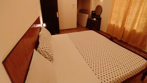 Habitació d'hotel amb llit, una taula de nit, aire condicionat, mirall i cortina.