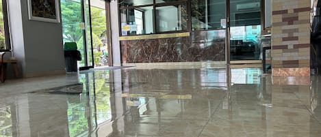 Un vestíbulo espacioso con suelo de mármol pulido, amplias ventanas y un mostrador de recepción moderno.