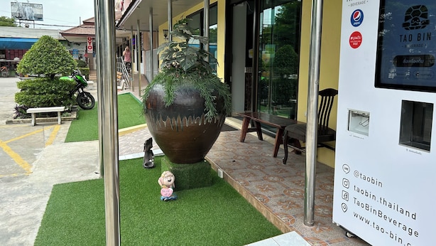 A building with a large planter, a bench, and a vending machine. - OKHOME HOSTEL (Bang Phli)