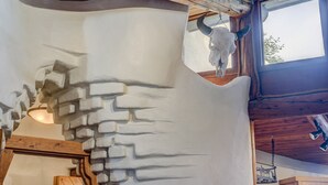 A rustic interior with a stone wall, wooden beams, and a cow skull decoration. - Eclectic Santa Fe Ranch Home + Casita with Hot Tub in Cave Creek (Cave Creek)