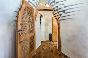 A narrow hallway with wooden doors and a checkered floor.