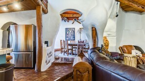 A rustic kitchen with a stainless steel refrigerator, wooden beams, and a dining area with a wooden table and chairs. - Eclectic Santa Fe Ranch Home + Casita with Hot Tub in Cave Creek (Cave Creek)
